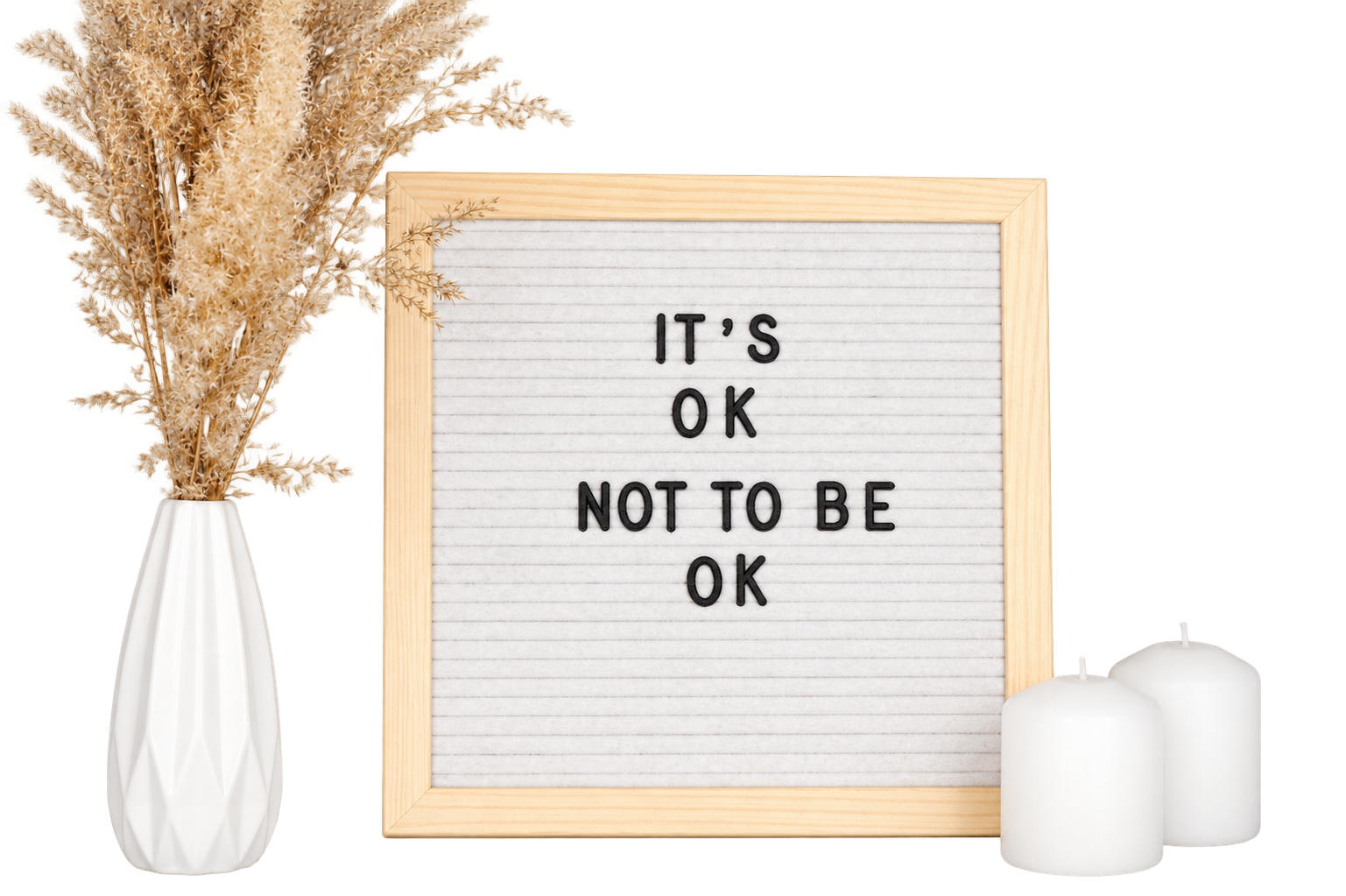 A letterboard reading It’s OK not to be OK, beside a vase and candles